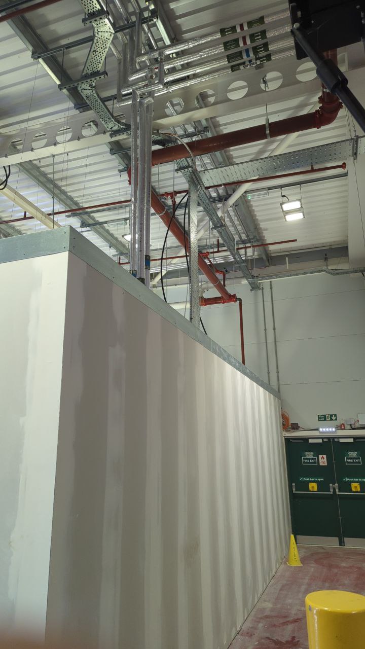 Internal fit-out works showing exposed ceiling services, partitions and fire exit doors